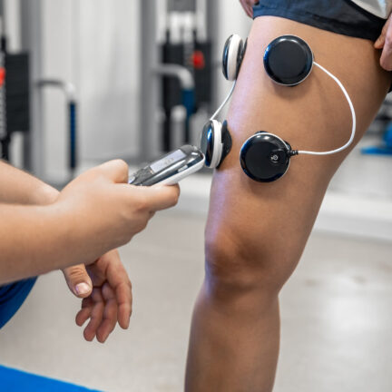 The procedure of myostimulation on the legs of a woman, rehab physiotherapy in gym, close up.