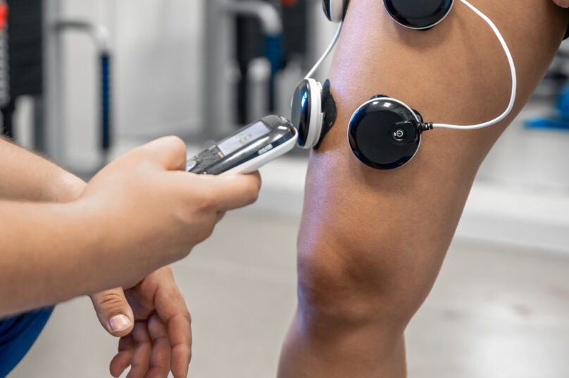 The procedure of myostimulation on the legs of a woman, rehab physiotherapy in gym, close up.